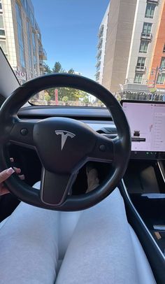 a person sitting in the driver's seat of a car with their hand on the steering wheel