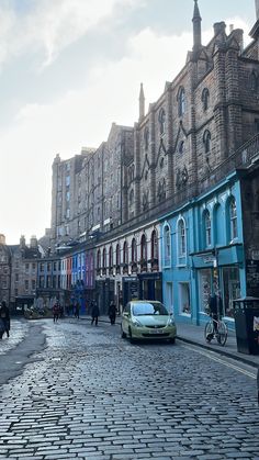 a car parked on the side of a cobblestone road in front of buildings