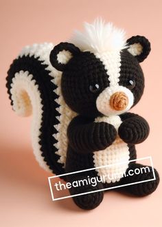 a crocheted black and white stuffed animal holding a piece of food in it's paws