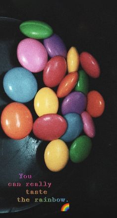 there is a bowl full of candy eggs on the table with words you can really taste the rainbow