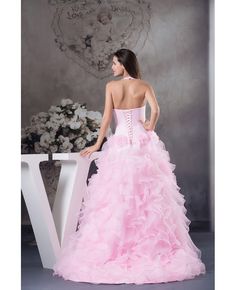 a woman in a pink dress standing next to a white table with flowers on it