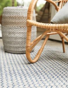 a wicker chair sitting on top of a blue and white rug