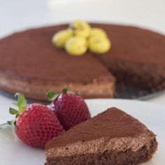 a piece of chocolate cake and two strawberries on a plate