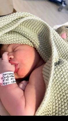 a newborn baby wrapped in a blanket and wearing a name tag