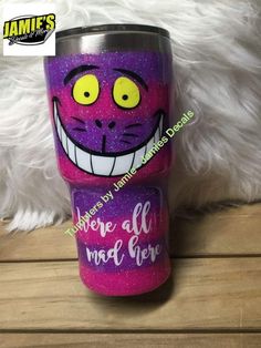 a pink and purple tumbler with an image of a cat's face painted on it