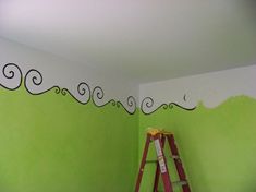 a ladder is in front of a green wall with black swirls painted on it