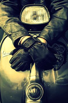 a person wearing black gloves sitting on a motorcycle