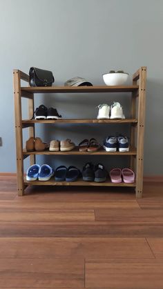 a wooden shoe rack filled with shoes on top of a hard wood floor next to a wall