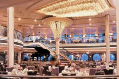 the inside of a cruise ship with tables, chairs and chandeliers on it