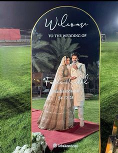 a bride and groom standing in front of a large mirror with the words welcome to the wedding of