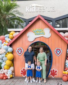 a family poses for a photo in front of a dog house with balloons all around it