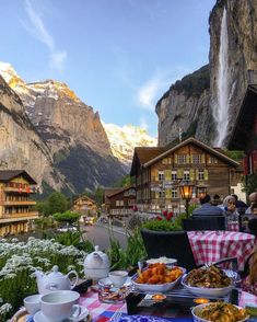 an outdoor dining area with mountains in the background and people eating at tables near by