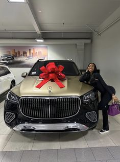 a woman standing next to a car with a large red bow on it