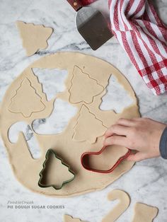 someone is making christmas cookies with cookie cutters