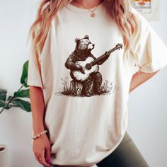 Bear Guitar T-Shirt - Embrace your love for music and bears with our Men's Bear Guitar Shirt, featuring a unique graphic of a bear playing guitar.  Perfect for music enthusiasts and bear lovers, this graphic tee is a stylish addition to your wardrobe. Shop now for the perfect bear-themed gift for yourself or a music-loving friend! Comfort Colors introduces the "Comfort Colors 1717" garment-dyed t-shirt; a fully customizable tee made 100% with ring-spun cotton.  The soft-washed, garment-dyed fabr Casual Cotton T-shirt With Bear Design, Cotton Graphic Tee With Bear Design, Summer Bear Print Crew Neck T-shirt, Casual Bear Design Short Sleeve T-shirt, Bear Design Graphic Tee With Short Sleeves, Graphic Tee With Bear Design, Bear Design Graphic Tee Short Sleeve T-shirt, Graphic Tee With Bear Design, Short Sleeve, Graphic Tee With Bear Design And Crew Neck