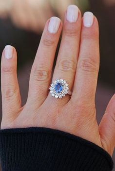 a woman's hand with a blue and white diamond ring on her left hand