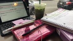 a laptop computer sitting on top of a desk next to a notebook and cup of coffee