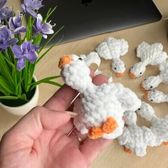 there is a small crocheted sheep on the table next to some purple flowers