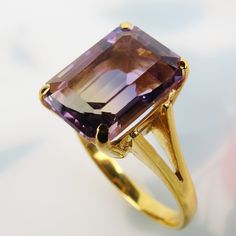 "A delightful golden purple 4 carat ametrine gemstone tops this vintage 1970s 14k yellow gold ring. Rarely found in nature, Ametrine is a quartz crystal with the presence of both amethyst and citrine. This bi-color quartz gem has 80/20 split zones of purple amethyst and yellow citrine. The citrine appears as a band with more purple surrounding it. The 11.2mm x 8.2mm x 6.2mm emerald-cut ametrine has nice translucency and clarity.  Four sturdy prongs hold the gem above a classic basket setting. Th Elegant Faceted Amethyst Ring In Yellow Gold, Gold Faceted Amethyst Ring, 14k Yellow Gold Emerald-cut Amethyst Ring, Faceted Amethyst Ring In Yellow Gold Fine Jewelry, Elegant Gold Faceted Amethyst Ring, Formal Gold Faceted Amethyst Ring, Elegant Gold Amethyst Ring With Faceted Detail, Elegant Gold Amethyst Ring With Faceted Cut, 14k Yellow Gold Amethyst Ring, Emerald Cut