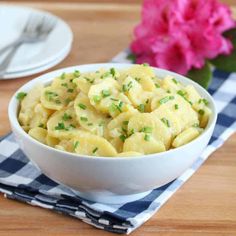 a white bowl filled with macaroni and cheese on top of a checkered napkin