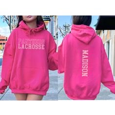 a woman wearing a pink sweatshirt with the words panther lacrosse printed on it, walking down a sidewalk