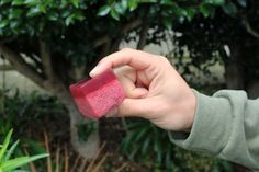 a person holding a piece of red soap in their hand