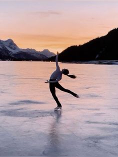 a woman skating on an ice covered lake at sunset with mountains in the background,