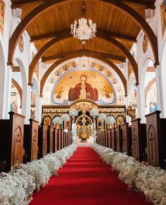 the interior of a church with red carpet and white flowers on the pews in front of it