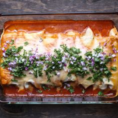 an enchilada covered in sauce and garnished with herbs