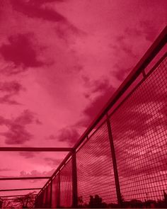 a red sky with some clouds in the background and a fence to the side that is next to it