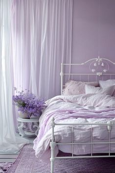 a white bed sitting in a bedroom next to a window with sheer curtains on it