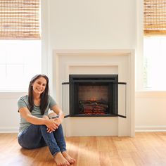 a woman sitting on the floor in front of a fireplace