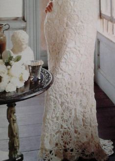 a woman standing in front of a mirror wearing a white dress and holding a cup