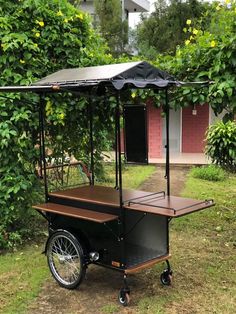 an outdoor cart with a canopy on the back in front of some bushes and trees