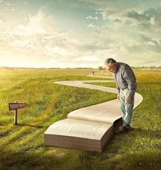 a man leaning over an open book in the middle of a field