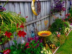 a garden filled with lots of flowers next to a wooden fence