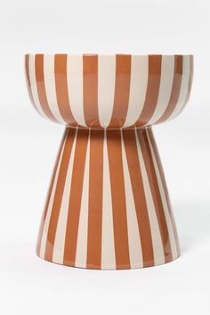 an orange and white striped vase sitting on top of a table