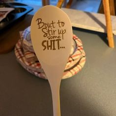 a white spoon with writing on it sitting on a table next to some plates and bowls