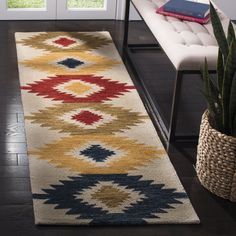 a rug with an abstract design on the floor next to a chair and potted plant