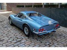 an old blue sports car is parked on the street