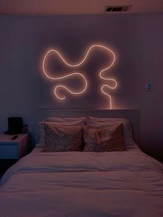 a white bed sitting in a bedroom under a neon sign on the side of it