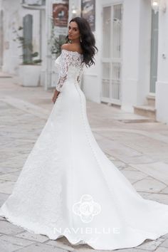 a woman in a white wedding dress is standing on the street with her back to the camera