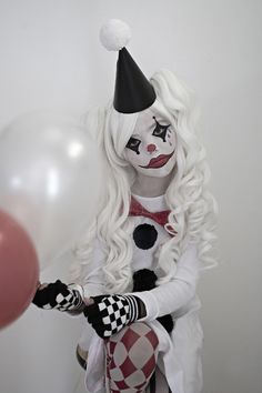 a woman dressed as a clown holding a balloon