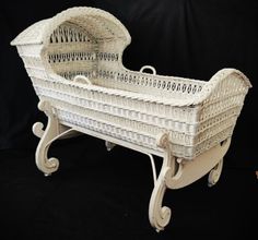 a white wicker baby crib sitting on top of a black background