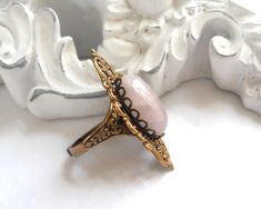 Lovely victorian style brass filigree ring with a beautiful pale rose quartz cabochon. The ring is made of oxidized brass componants, american made and is adjustable. Cabochon size: 13 x 18 mm. Please note: Due to the natural material of the cabochon inlay, color and pattern differences may occur. For more jewelry please visit our shop: http://www.minouc.etsy.com For combined shipping please contact us. We also combine shipping with our other Etsy shop where we sell vintage fabrics and finds fro Victorian Style Rings, Pink Victorian, Brass Filigree, Rose Quartz Ring, Filigree Ring, Pink Ring, Quartz Ring, Vintage Fabrics, Natural Material