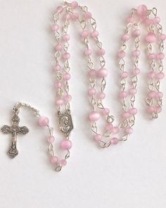 Handmade with small 4mm and 6mm pink cats eye beads and silver tone metal wire. I love the cats eye beads because of the ribbon of light that appears and follows the sun. Small Our Lady of Fatima medal and small crucifix. Comes with a gift pouch Pink Rosary With 8mm Round Beads, Adjustable Pink Cross Rosary, Pink Rosary With Miraculous Medal As A Gift, Pink Rosary With Round Beads For First Communion, Pink Rosary For First Communion, Pink 8mm Beads Crucifix Jewelry, Pink Rosary With 8mm Beads For Gift, Pink Rosary With 8mm Beads As Gift, Pink Rosary