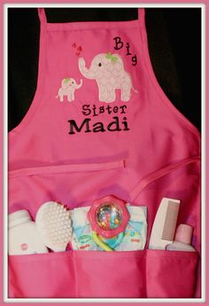 a pink apron with an elephant and baby items in it