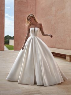 a woman in a white wedding dress is standing on the floor with her hand out