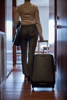 a woman is walking down the hall with her suitcase