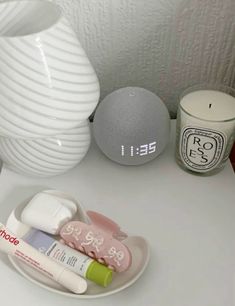 an alarm clock sitting on top of a white table next to candles and other items